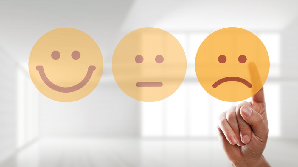 A hand is selecting a sad emoticon or emoji