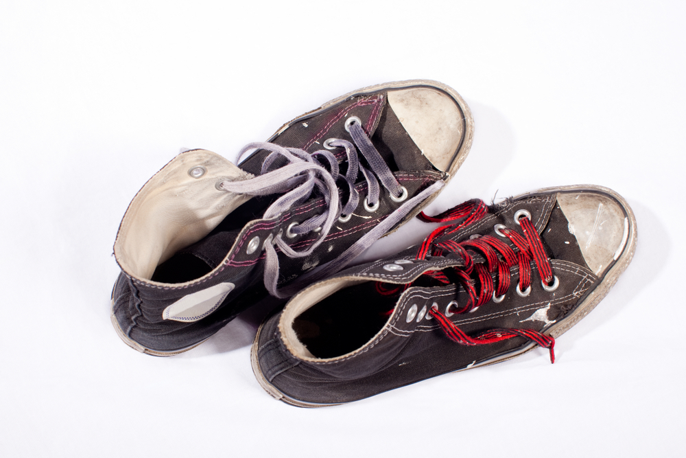 A pair of dark, old, used mismatched shoe