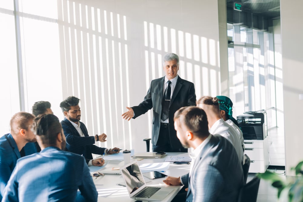 A business executive talking at the head of the table at a conference