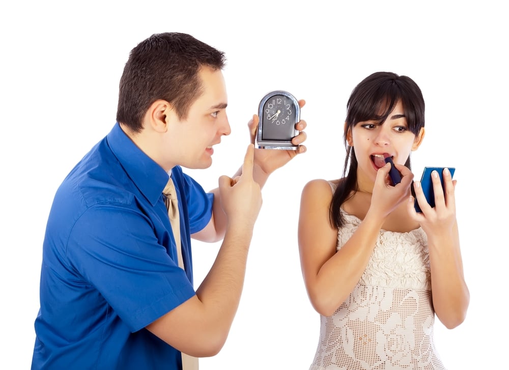 A man angry that they are late because of his wife, she continues to apply her makeup