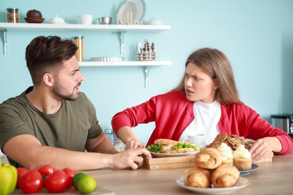 Young man trying to take tray of food that is in front of the woman, she drags it back