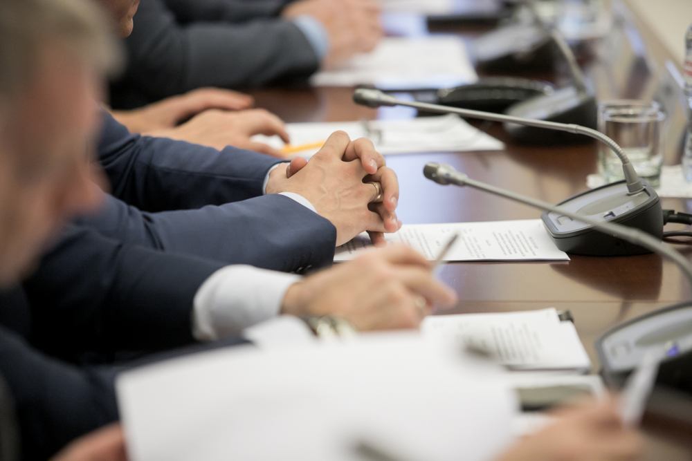 Politician sitting on a table with their hands in front of them