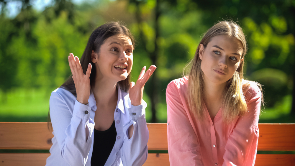 A young woman feeling tired of the conversation with her talkative friend
