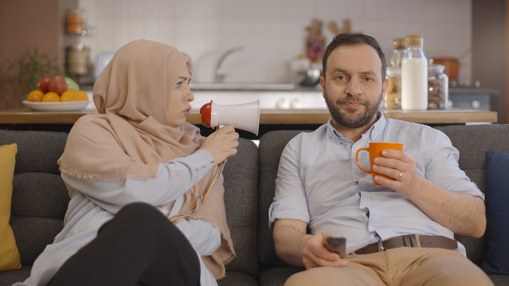 A man not listening to his Muslim wife talking with a megaphone close to him