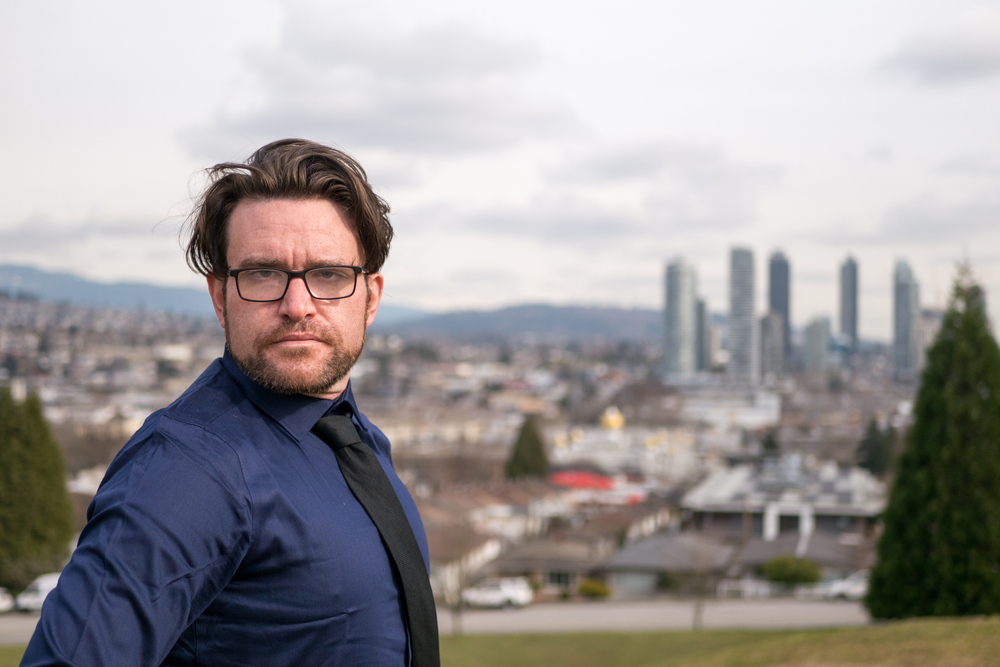 A narcissistic man wearing a dark suit and glasses