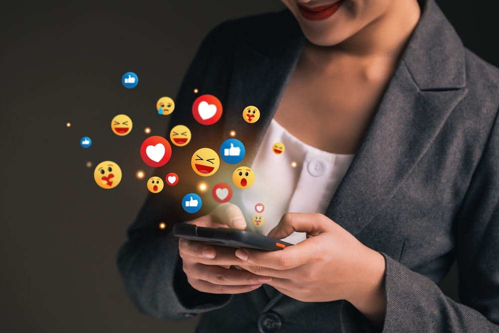 A business woman on suit typing on her smartphone and chatting on social media with the use of emojis