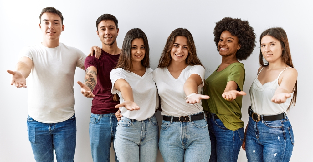 Group of young friends standing together with their hands stretched