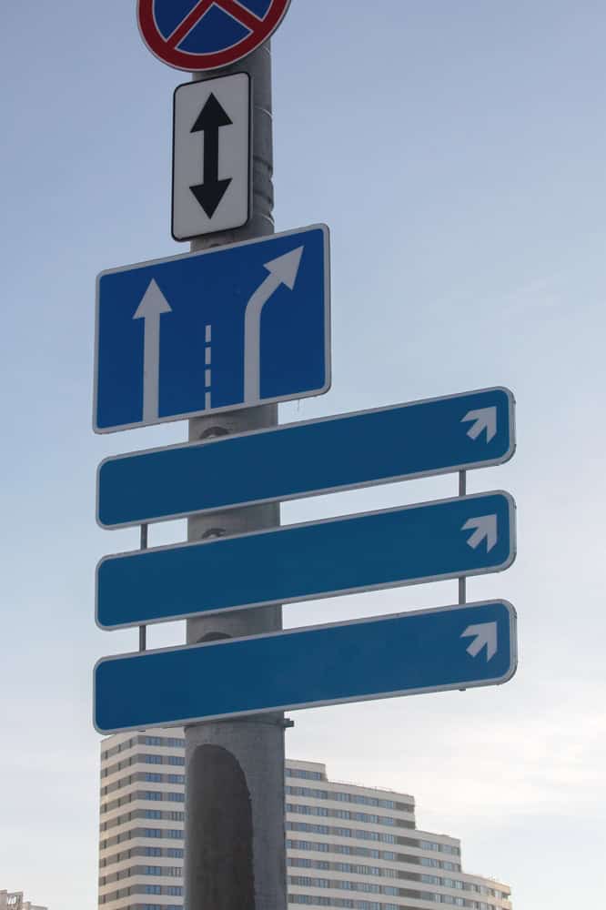 Stacked signs on a pole by the road