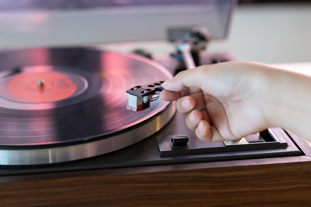 A woman hand putting a record player needle on a vinyl record