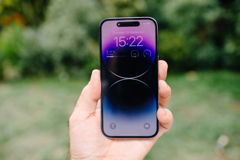 A man holding up his iPhone and it is showing the home screen 