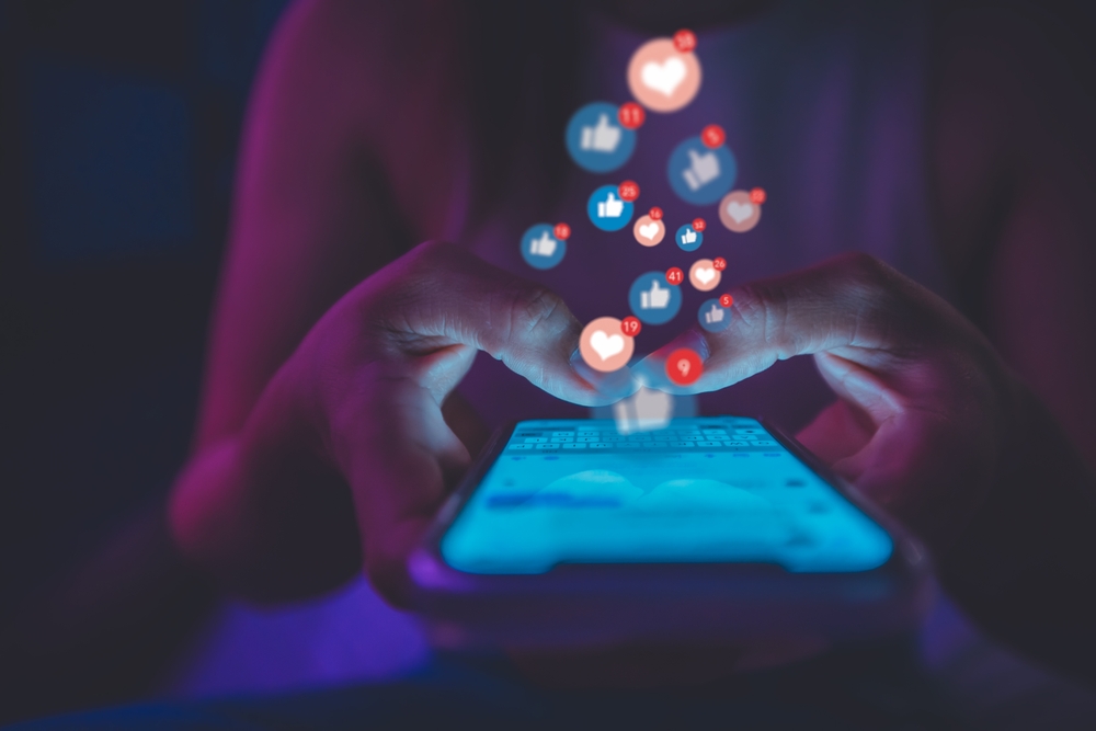 A hand using emojis on social media