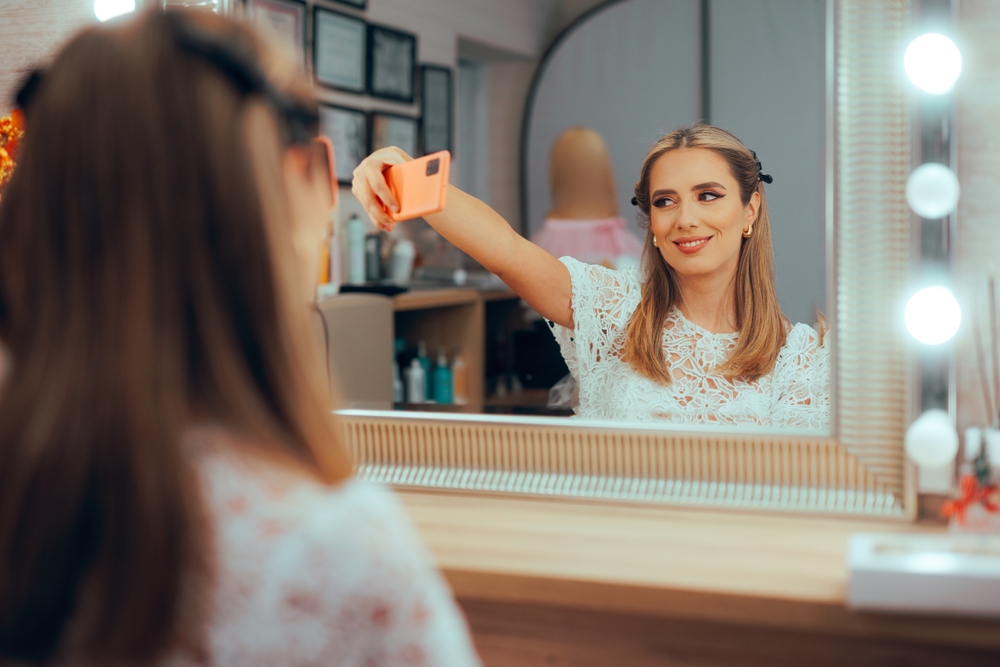 A narcissistic yung lady sitting in front of the mirror and taking a picture