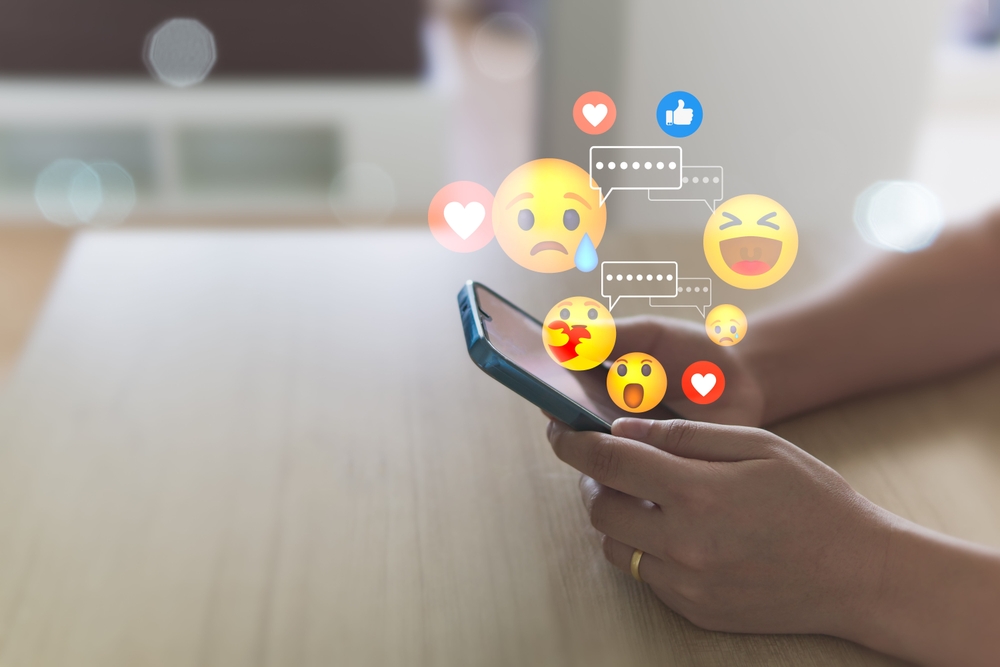 A man typing on his smartphone and using emojis