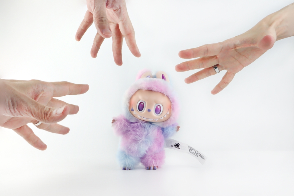 Three people reaching out to get a labubu doll