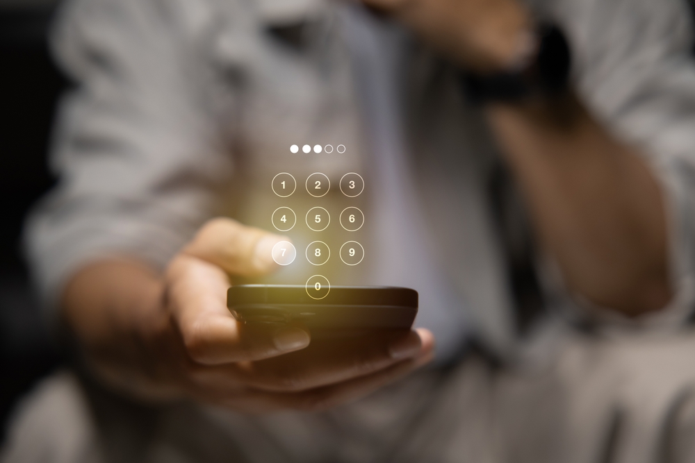 A man typing his password into his phone