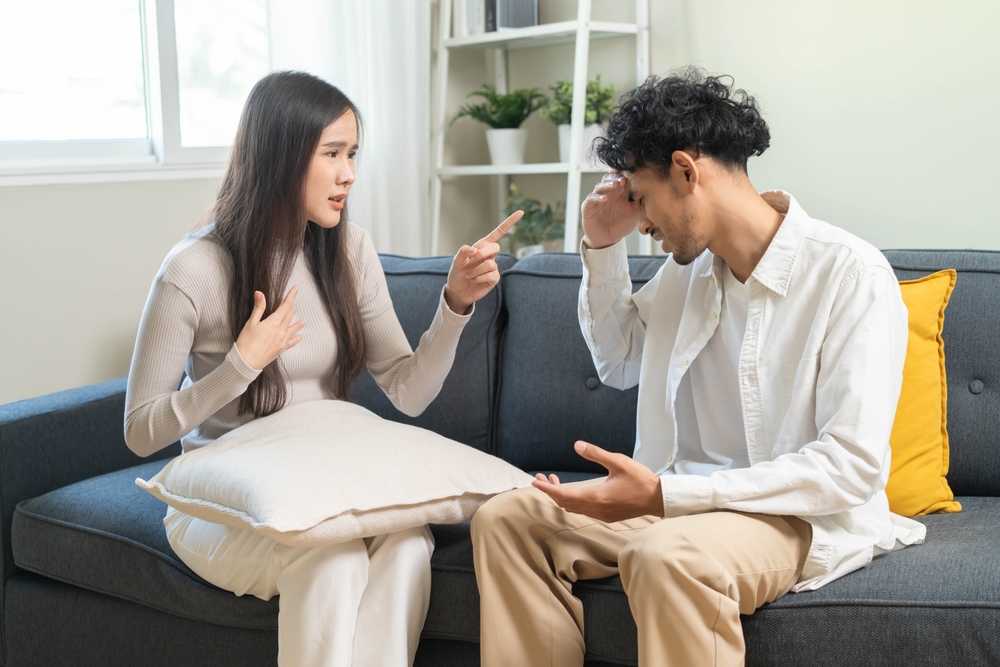 A young couple sitting in the living room and having an argument