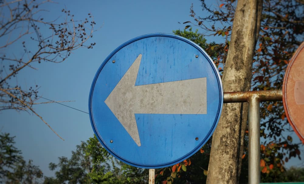 A left pointing arrow on a blue road sign