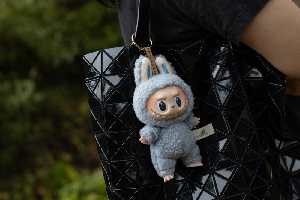 A blue labubu doll hanging from a black bag