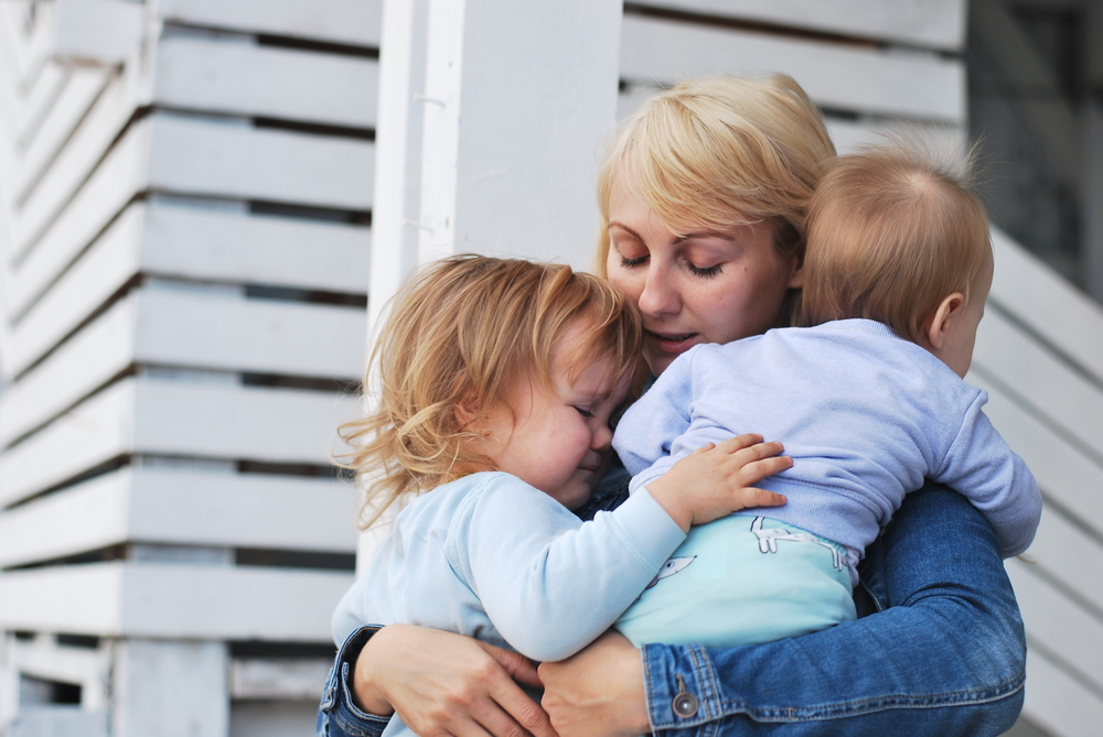A young mother holding her two babies
