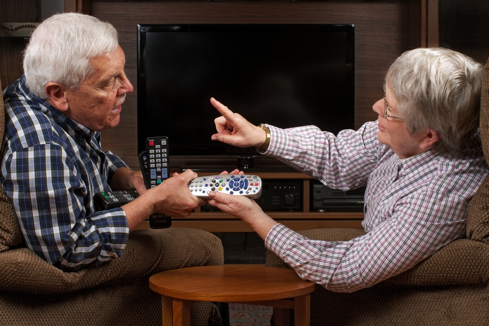 A senior elderly couple fighting over the TV remote