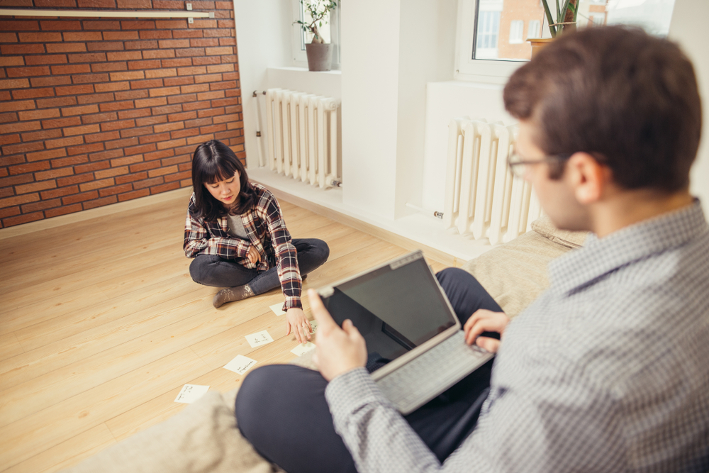 Two young students with one playing card games and the other using his laptop