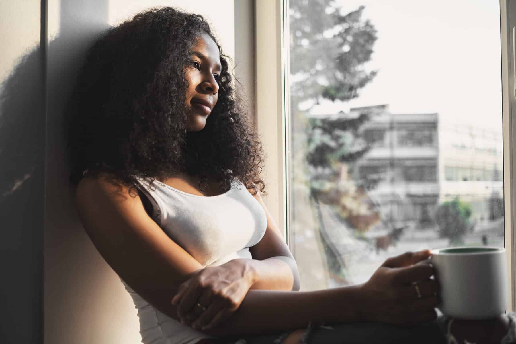 A woman siting alone with her thoughts and a cup of tea.