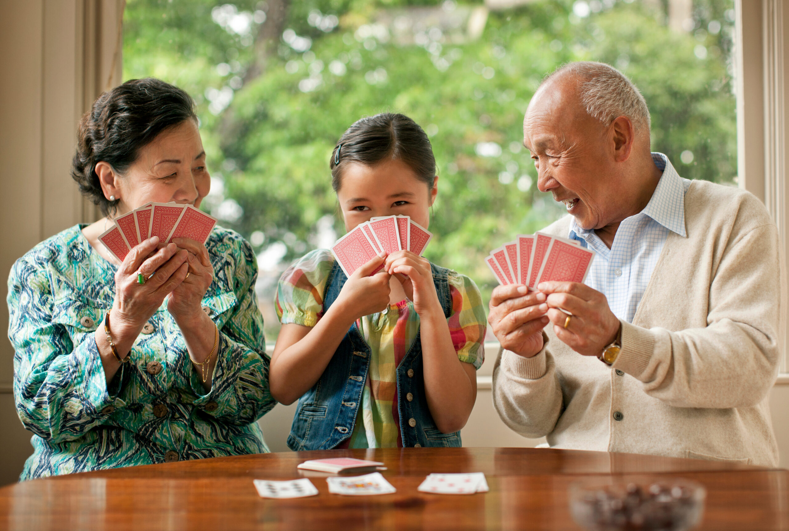 A young girl having fun playing cards at her grandparent's house.