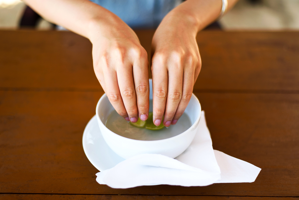 A woman washing her fingers in lime water at a restaurant. 