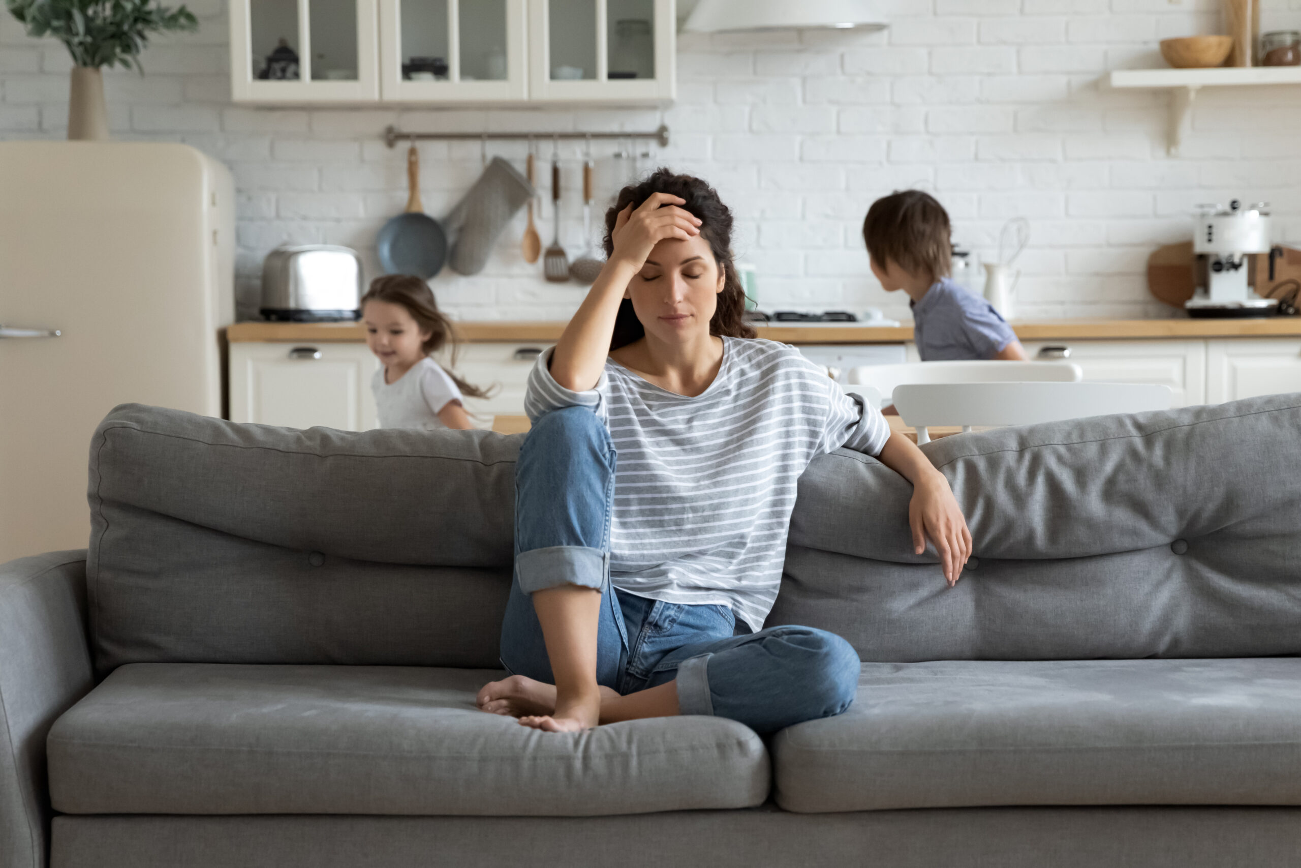 Frustrated mother with kids running around her.