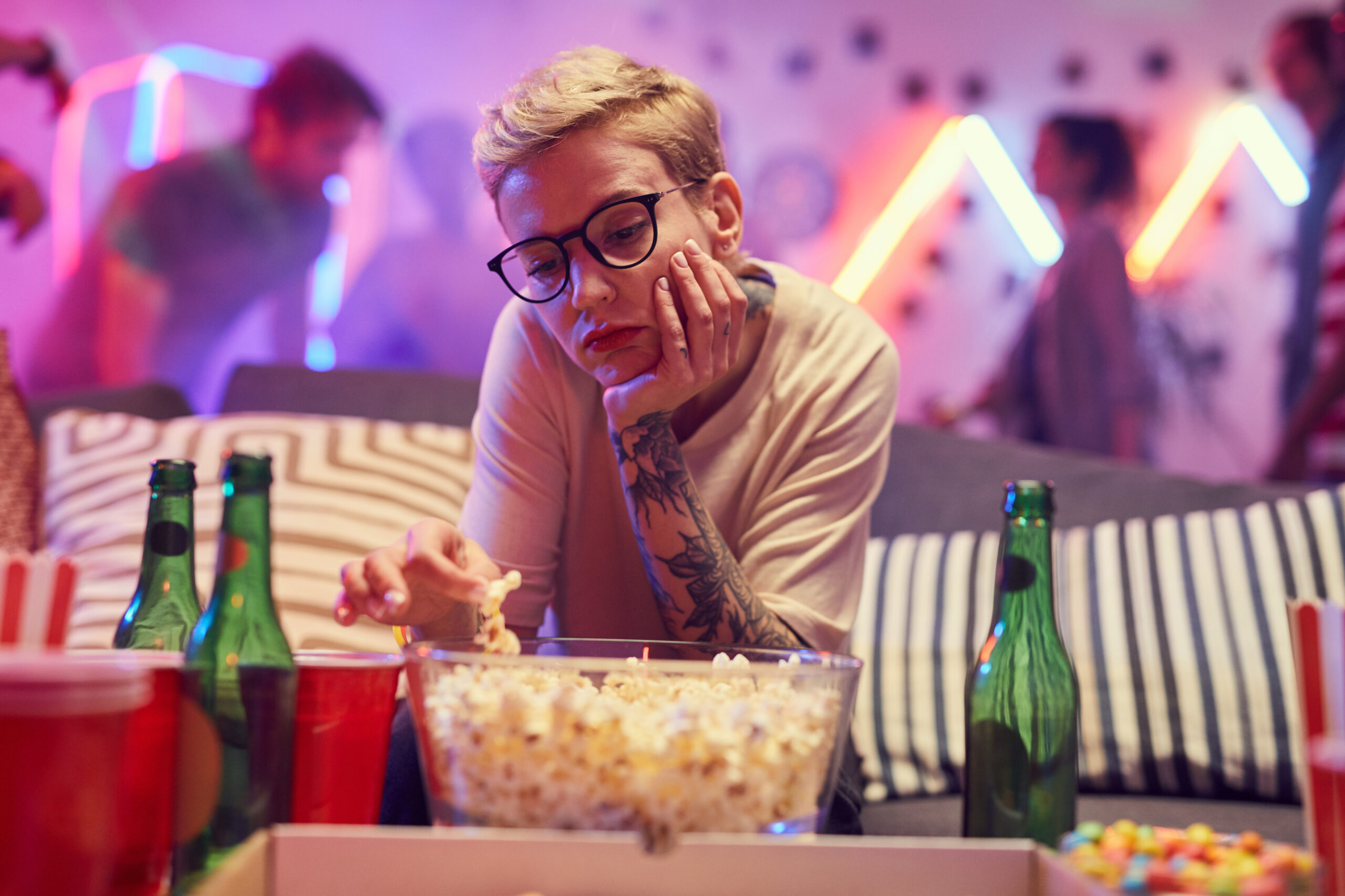 A young woman sitting alone while bored at a party.