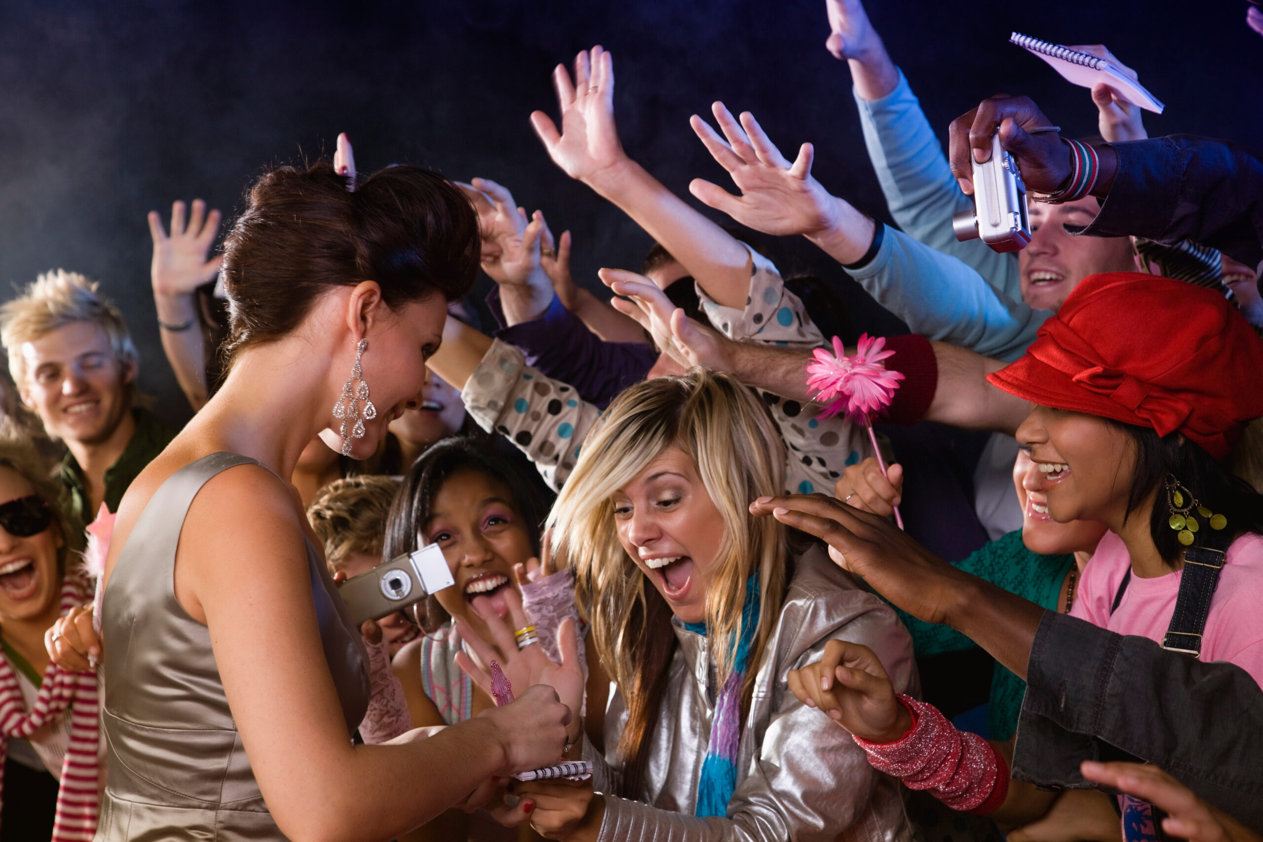 A celebrity signing autographs for screaming fans.
