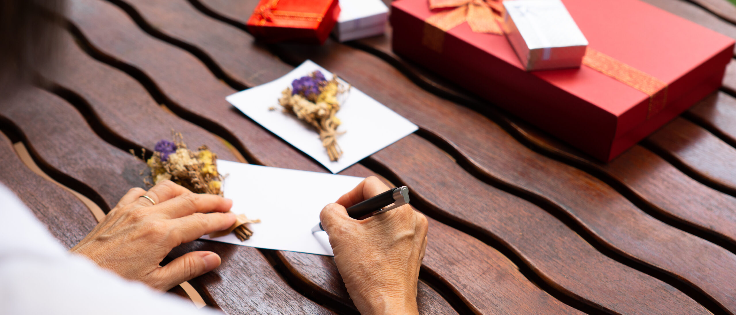 An older woman signing a birthday card to her loved one.