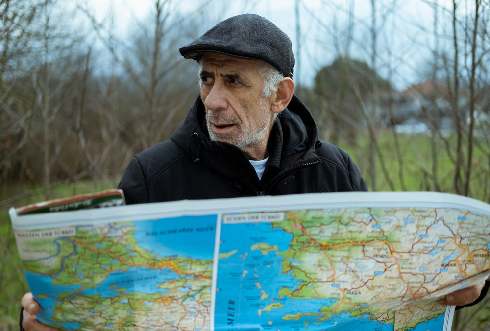 An old senior man checking his map after he lost his way