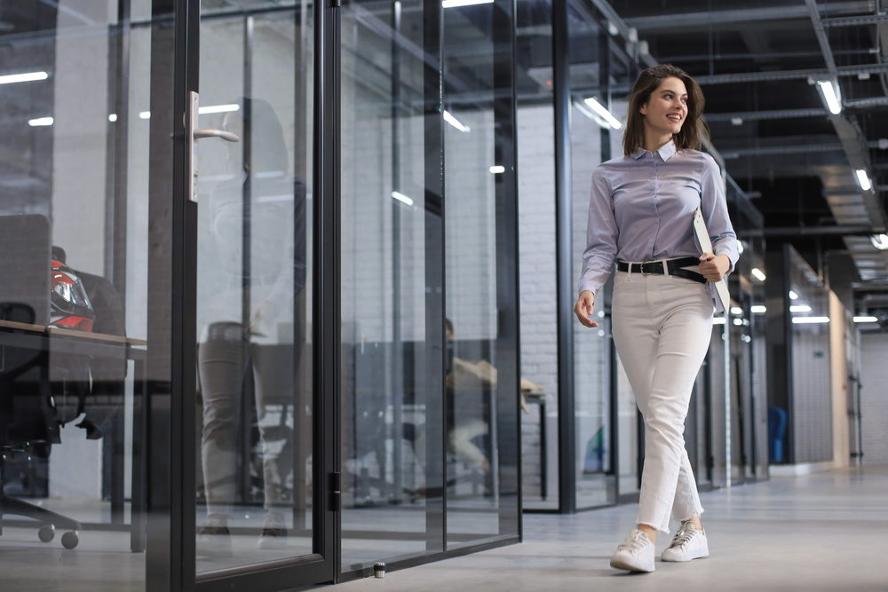 A confident business woman walking along the office corridor with documents in her hand