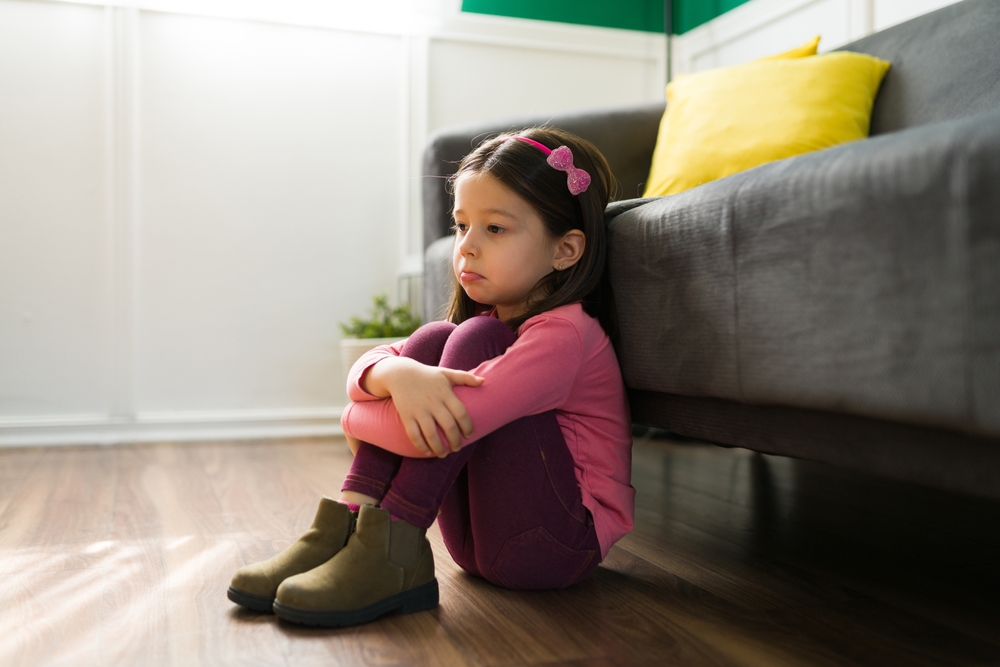 A child sitting on the floor alone looking sad