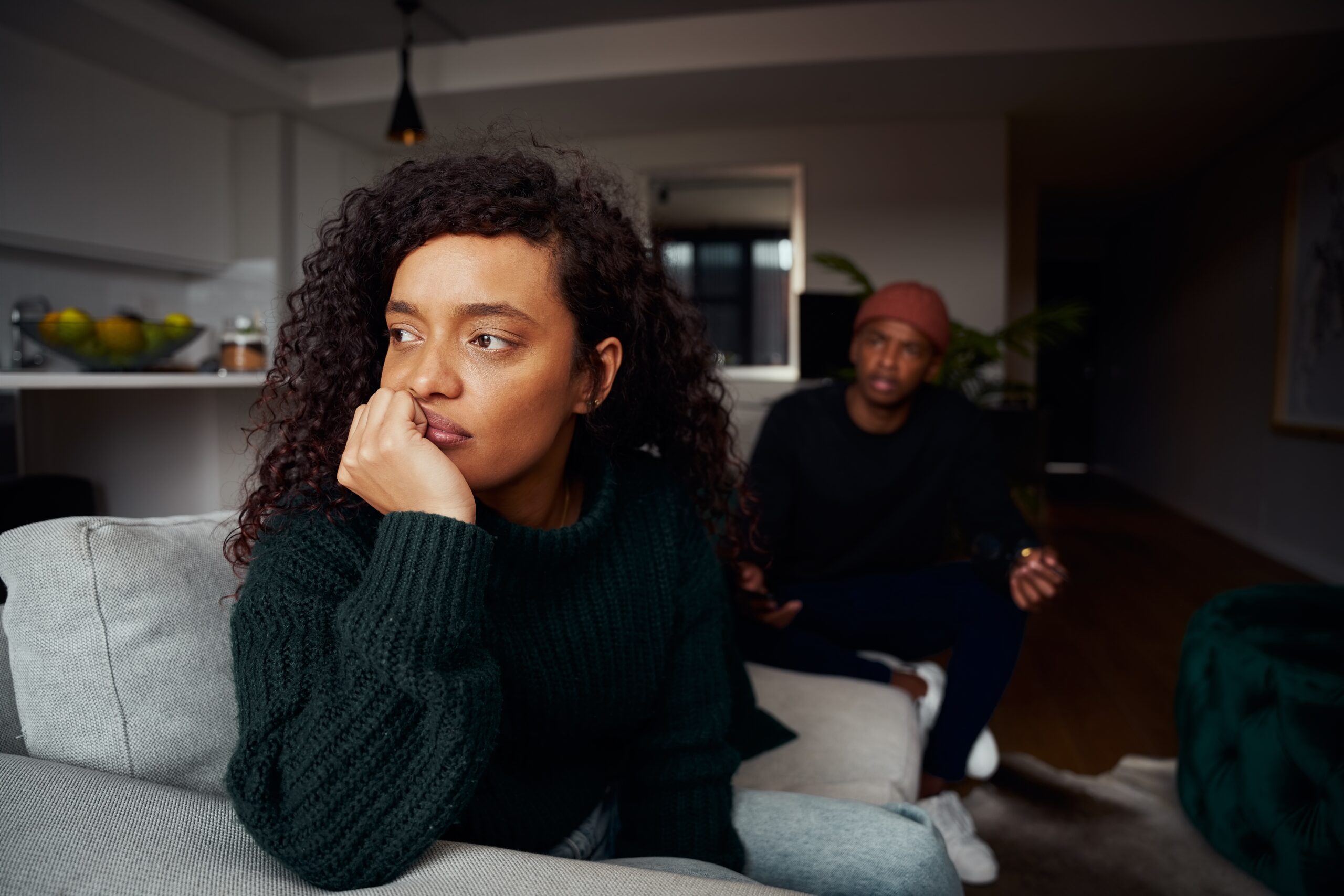 An unhappy couple sitting on the couch during an argument.