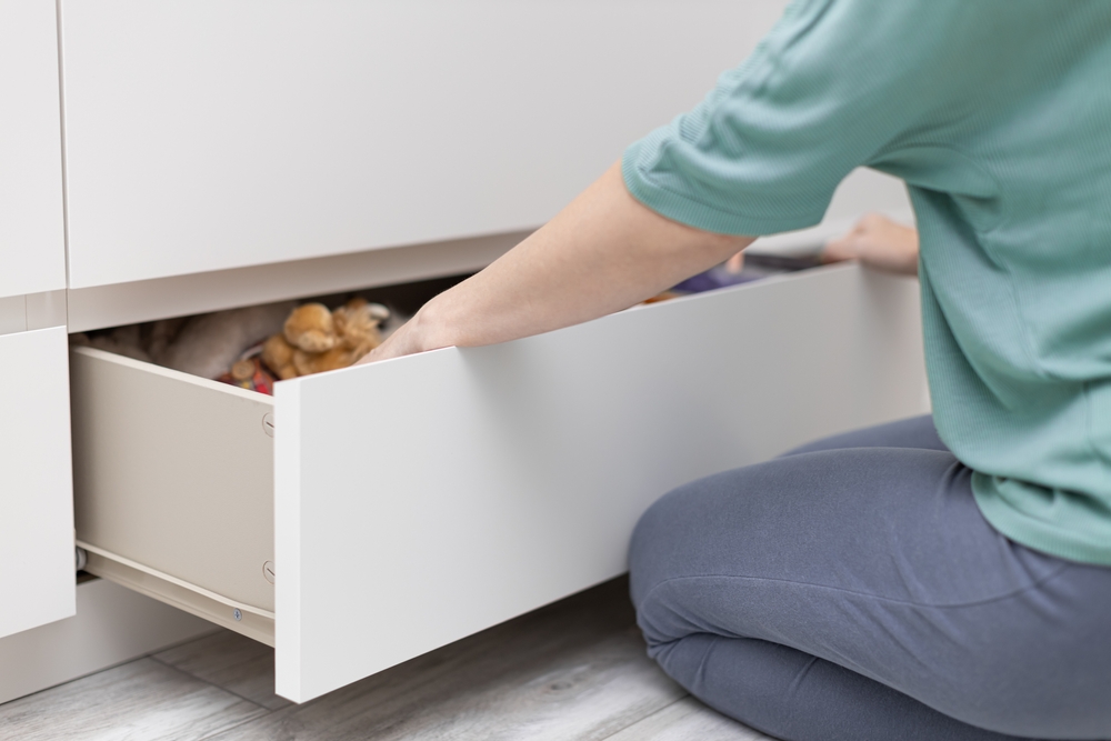 A woman sits on her knees while going through the contents of her drawer