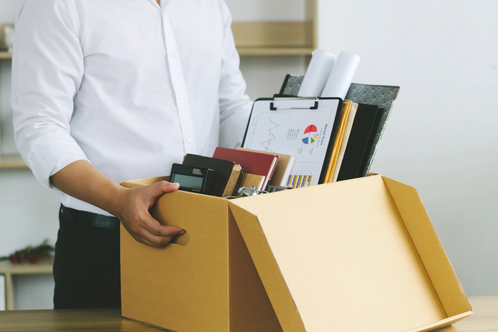A amn packing up his desk into a box after losing his job and getting fired or resigning
