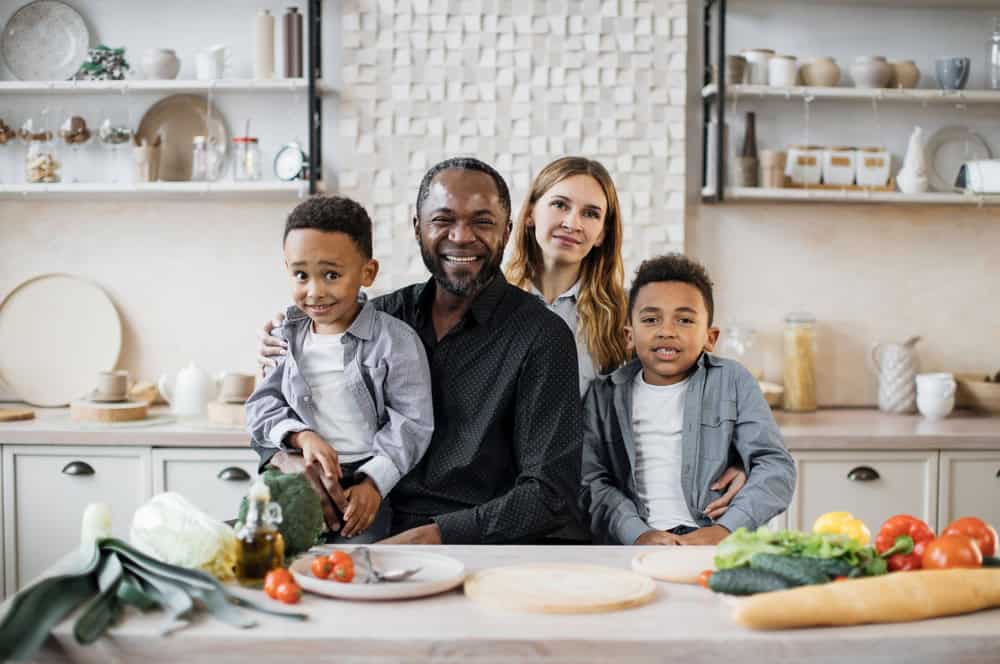 A racially diverse family in the kitchen with their healthy food in front of them