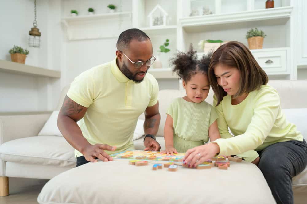 A racially diverse family with their little doing playing with puzzles