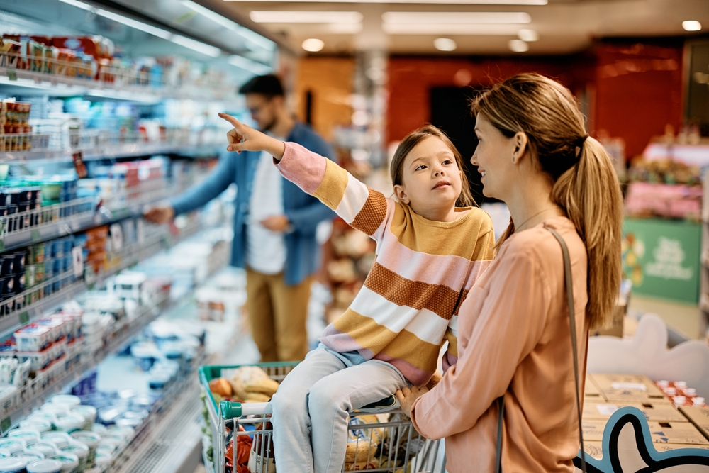 A child talking with her mother in the grocery store.