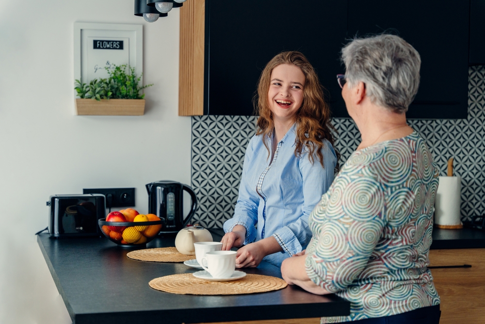 A cute teenage granddaughter having a conversation with her grandmother and laughing