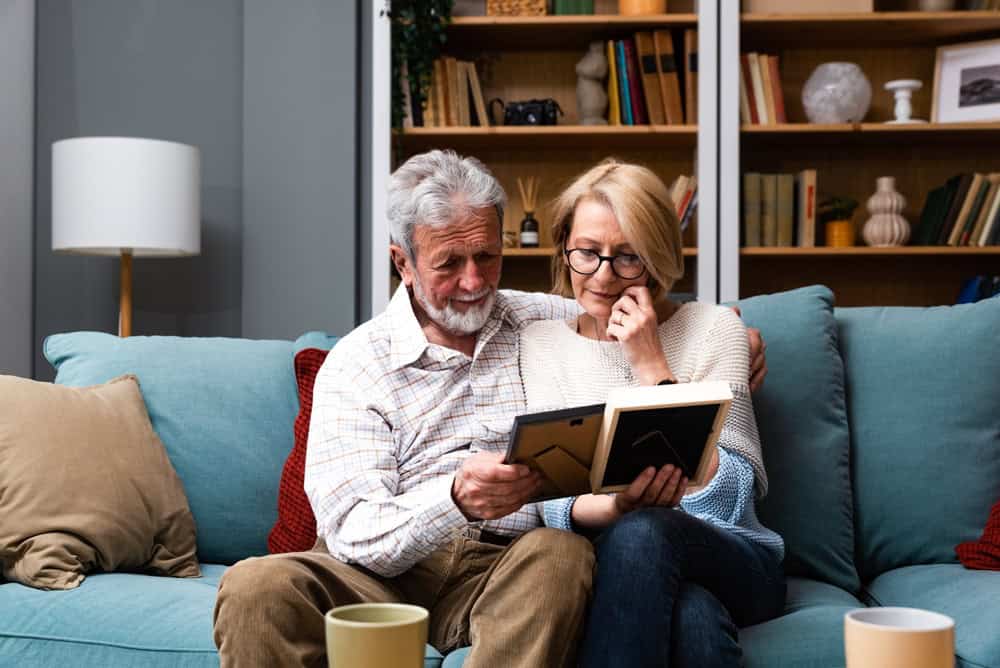 A senior couple on the couch looking at photographs together. 