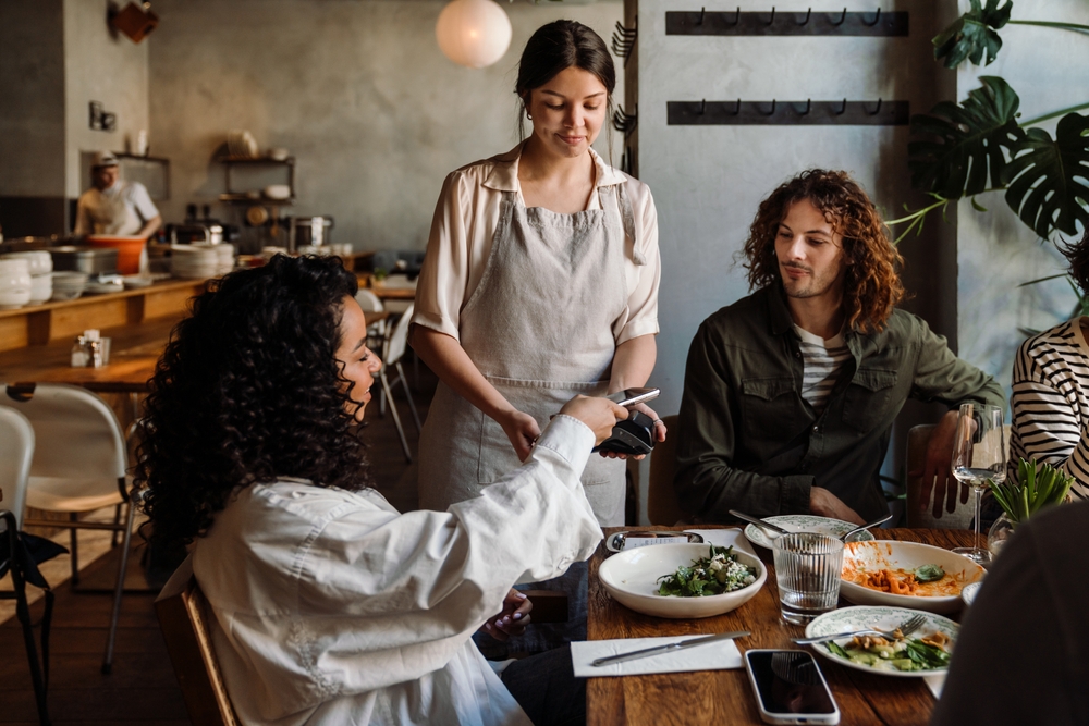A young woman buying dinner for her and her friends and paying the bill