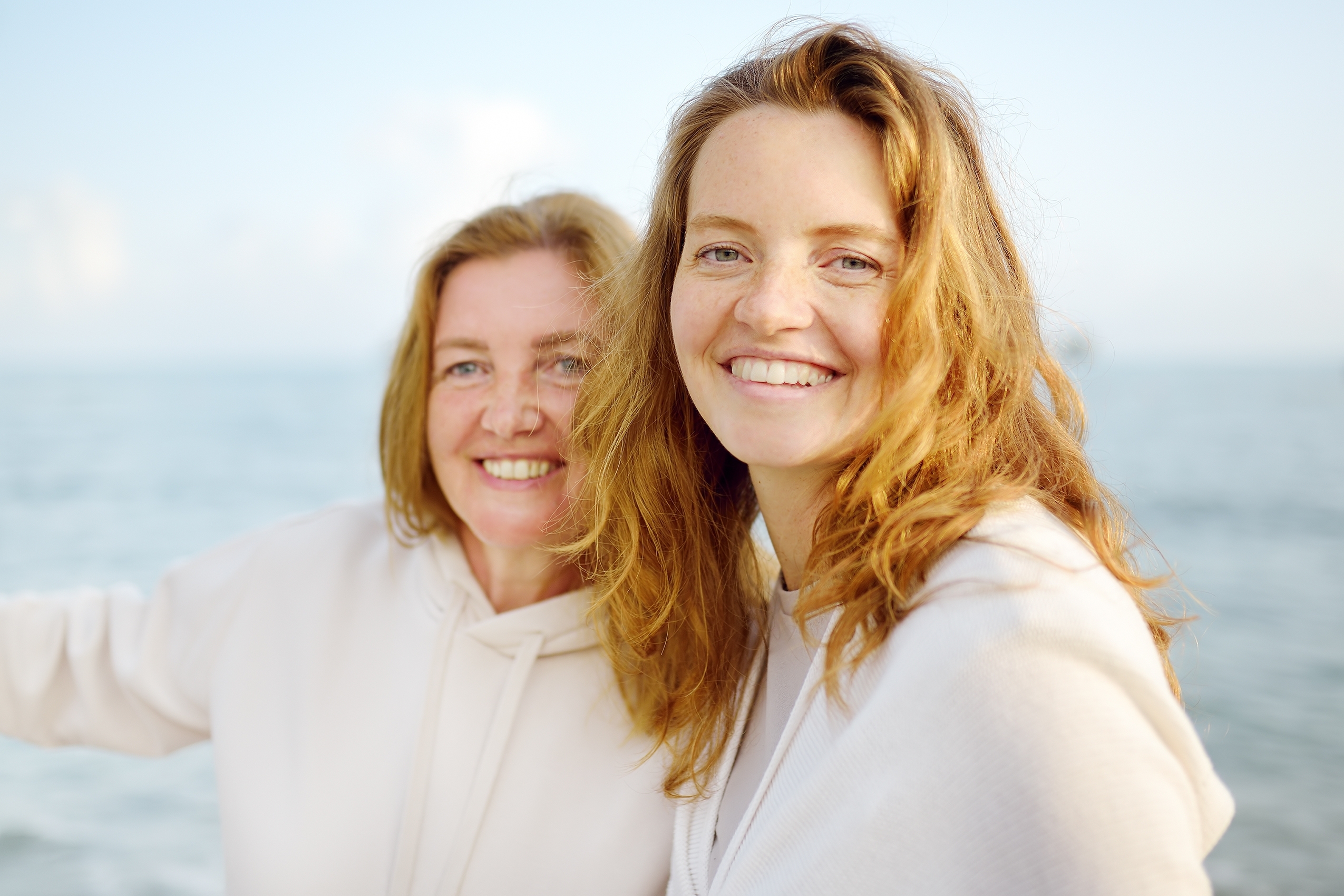 An adult woman having a walk on the beach with her mother.