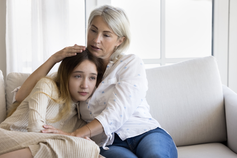 A compassionate mother comforting her daughter on the couch.