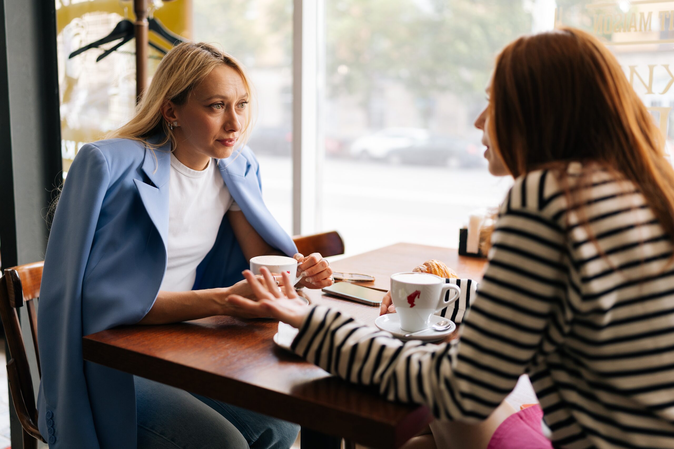Two sisters at a coffee shop having a serious conversation.