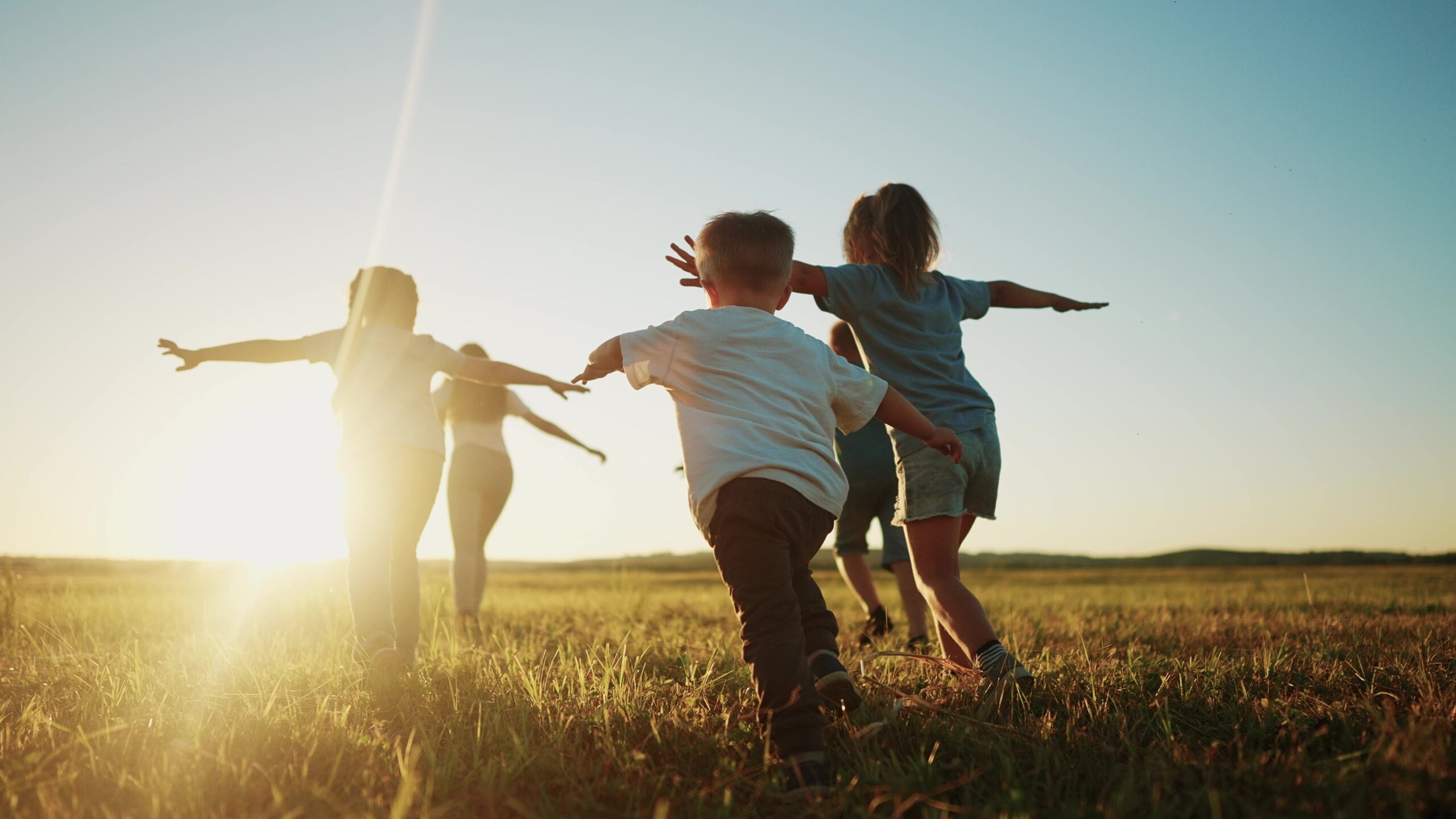 A group of children are playing outside together as the sun is setting.