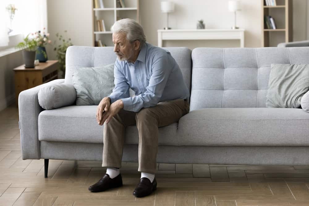 Lonely senior man sitting and reflecting on his couch.