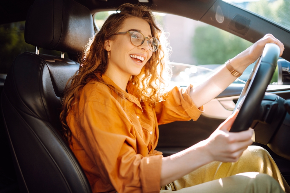 A happy young woman driving her car to work